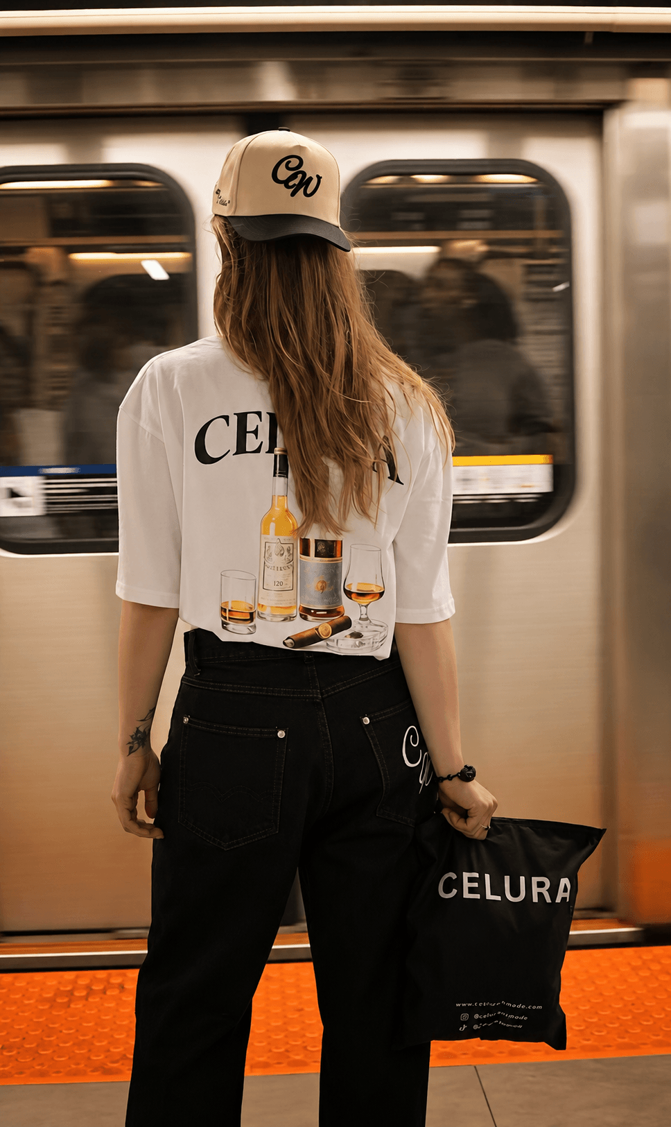 Celura cap, graphic tee and denim at a train platform